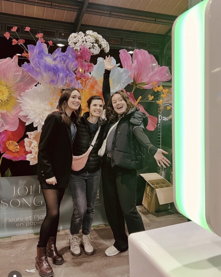 Invitées posant devant un photocall fleuri à côté d’une borne photo à Rennes