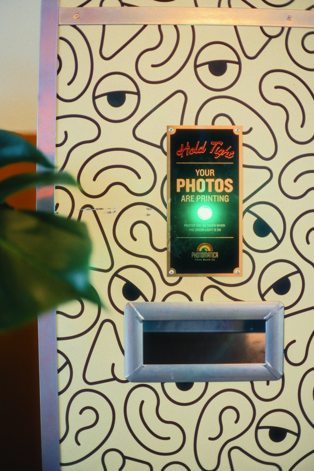 Borne photobooth avec fond décoratif en train d'imprimer les photos des invités pendant un événement